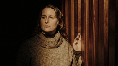 A woman stands by a red partition wall dimly lit
