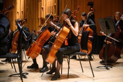 Young musicians playing the double bass during a performance, dressed in black