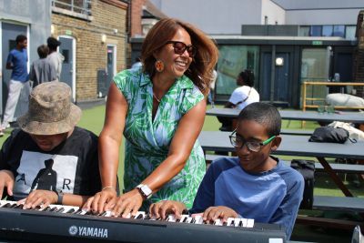 Nikki Yeoh with MEI students playing keyboard